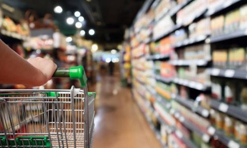 woman hand hold shopping cart with Abstract blur supermarket aisle background